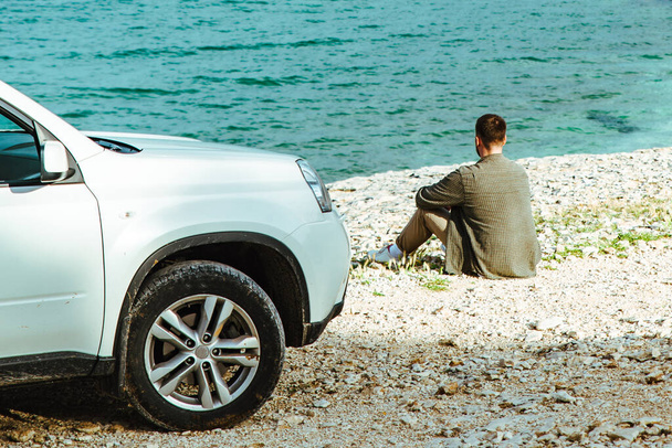 海辺の車の近くに立ってる男。ロードトリップのコンセプト。夏休み - 写真・画像