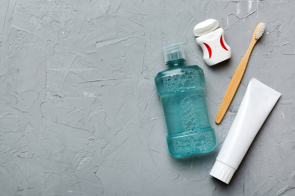 Mundspülung und andere Mundhygieneprodukte auf farbiger Tischplatte mit Kopierraum. Flach lag er. Zahnhygiene. Mundpflegeprodukte und Platz für Text auf hellem Hintergrund. Konzept. - Foto, Bild