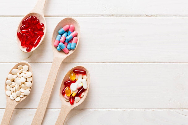 Vitamin capsules in a spoon on a colored background. Pills served as a healthy meal. Red soft gel vitamin supplement capsules on spoon. - Fotoğraf, Görsel
