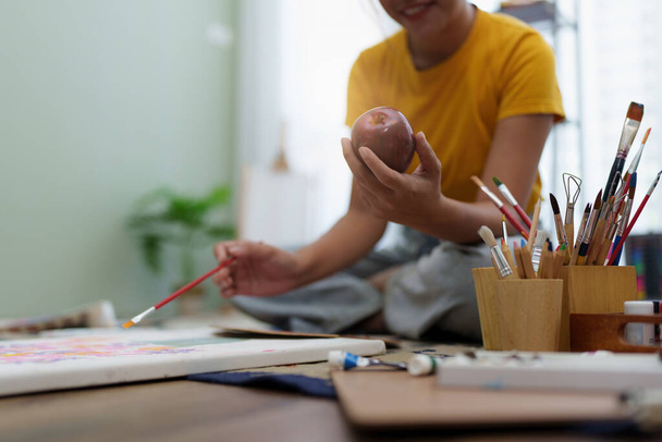 Joyful young female artist painting on canvas at workshop. - Photo, Image