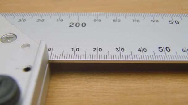 Square angle ruler. Construction Carpenter ruler on a wooden surface L shape straightedge.Square angle ruler lying on a table, ready to be used in construction, woodworking. Close up, macro. Wooden surface, background. - Filmati, video