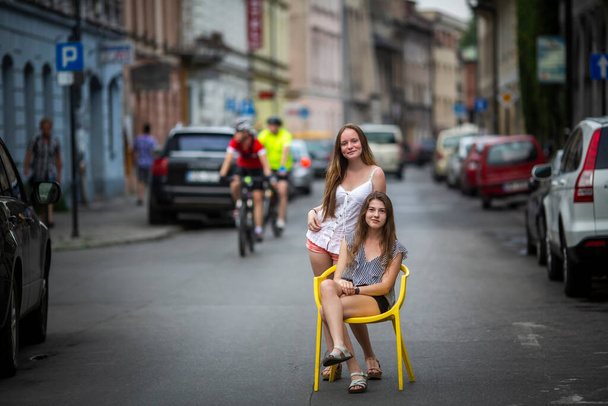 Two teengirls girlfriends pose in the middle of the street in the Krakow old town, Poland. - Photo, Image