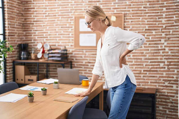 Genç sarışın iş kadını ofiste sırt ağrısı çekiyor. - Fotoğraf, Görsel