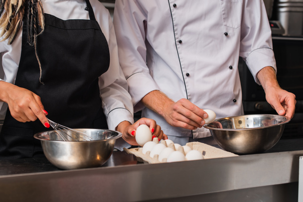 cropped view of chefs holding raw eggs while cooking together in kitchen  - Fotoğraf, Görsel