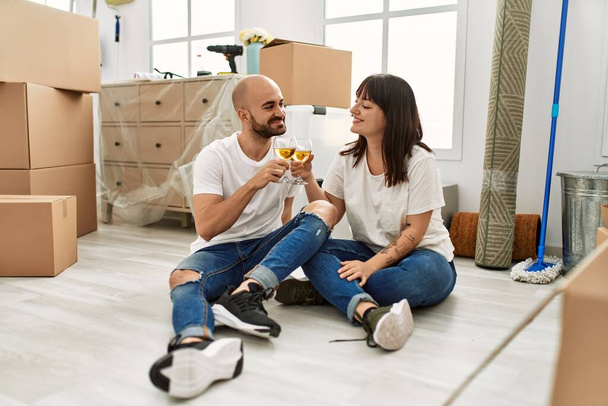 Genç İspanyol çift yeni evinde şampanyayla kadeh kaldırırken gülümsüyor.. - Fotoğraf, Görsel