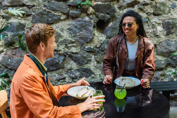 happy interracial friends smiling during lunch in outdoor cafe terrace - Foto, Imagen