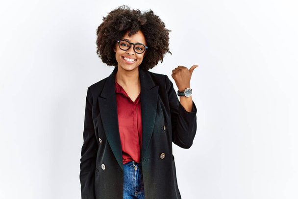 Afričanky americká žena s afro vlasy na sobě obchodní bunda a brýle s úsměvem šťastný obličej při pohledu a ukazuje na stranu s palcem nahoru.  - Fotografie, Obrázek