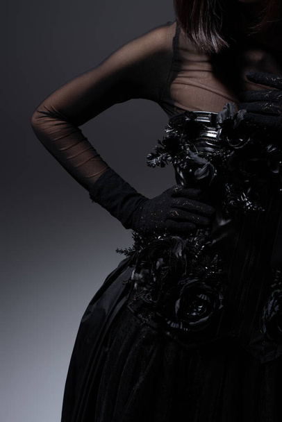 cropped view of woman in black gothic dress and gloves posing with hand on hip on dark grey - Φωτογραφία, εικόνα
