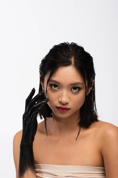 young asian woman with bare shoulders and hand in black paint posing isolated on white - Valokuva, kuva