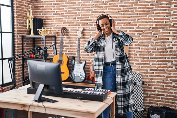 African american woman musician listening to music dancing at music studio - 写真・画像