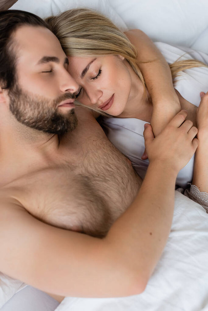 top view of bearded man embracing woman while sleeping on bed in morning - Foto, Bild
