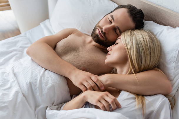 bearded man embracing blonde woman while sleeping in morning - Fotoğraf, Görsel