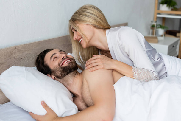 blonde woman in robe waking happy bearded man in morning - Photo, Image
