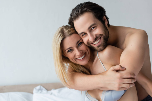 happy couple in love hugging and smiling at camera in bedroom - Foto, Bild