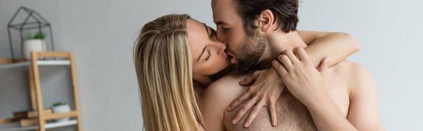сексуальная блондинка с закрытыми глазами целует мужчину без рубашки дома, баннер - Фото, изображение