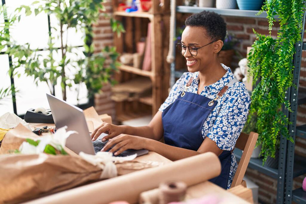 African american woman florist smiling confident using laptop at florist - Photo, Image