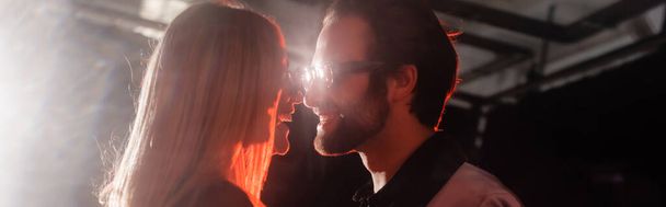 Вид сбоку пары в солнцезащитных очках, улыбающейся во время вечеринки, баннер  - Фото, изображение