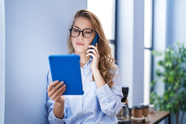 Giovane donna bionda business worker che parla sullo smartphone utilizzando touchpad in ufficio - Foto, immagini