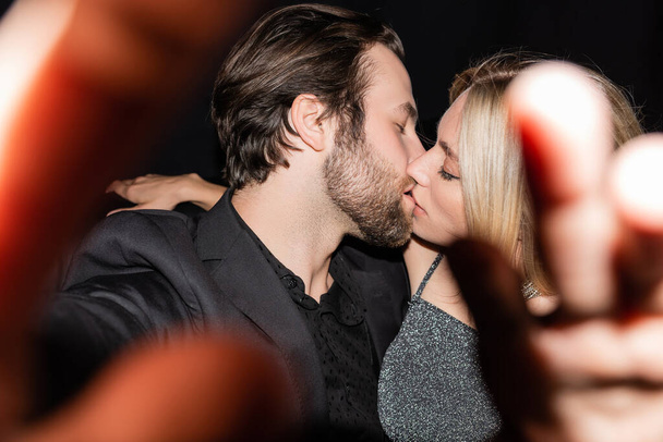 Side view of stylish couple kissing during party on black  - Foto, immagini