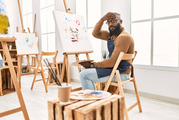 Afrykański amerykański artysta malarstwo człowiek na płótnie w studio sztuki podkreślił i sfrustrowany ręką na głowie, zaskoczony i zły twarz  - Zdjęcie, obraz