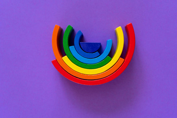 Abstract rainbow background. Wooden kids toys on violet paper. Educational toys blocks, rainbow. Toys for kindergarten, preschool or daycare. Copy space for text. Top view - 写真・画像