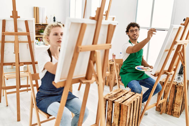 Young artist couple smiling happy painting at art studio. - Φωτογραφία, εικόνα