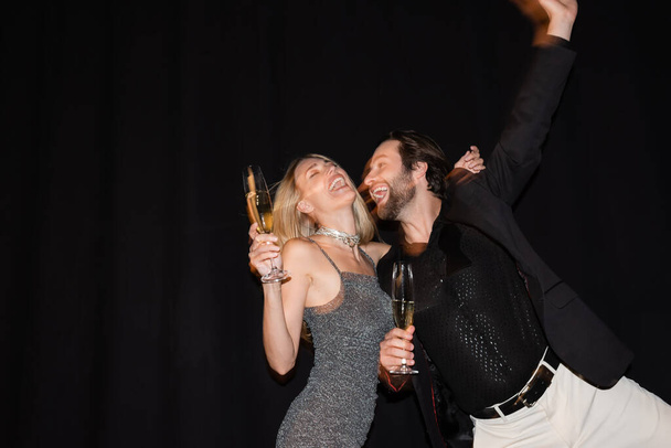 Движение размытие возбужденного купе с шампанским во время вечеринки изолированы на черный  - Фото, изображение
