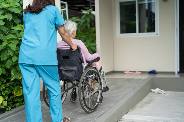 Aide et soins aux aidants Aînée asiatique ou vieille dame âgée patiente assise en fauteuil roulant sur la rampe d'accès à l'hôpital de soins infirmiers, concept médical solide et sain - Photo, image