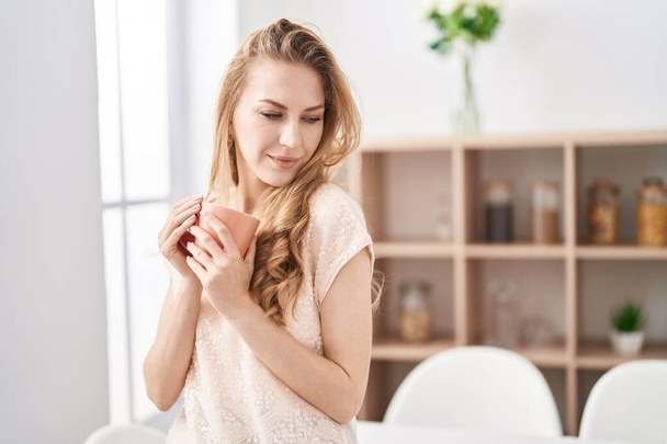 Jeune femme blonde souriante confiance boire du café à la maison - Photo, image