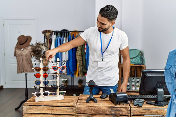 młody arabski człowiek sklepikarz dotykając okulary pracy w sklepie odzieżowym - Zdjęcie, obraz