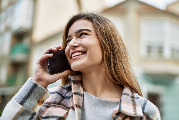 Mujer rubia joven hablando en el teléfono inteligente en la calle - Foto, imagen