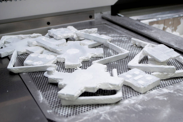 Детально распечатанные объекты на порошковом 3D принтере и покрытый белый полиамидный порошок крупным планом. Технология Multi Jet Fusion MJF. 3D прототипы, созданные с помощью новой прогрессивной технологии 3D печати - Фото, изображение