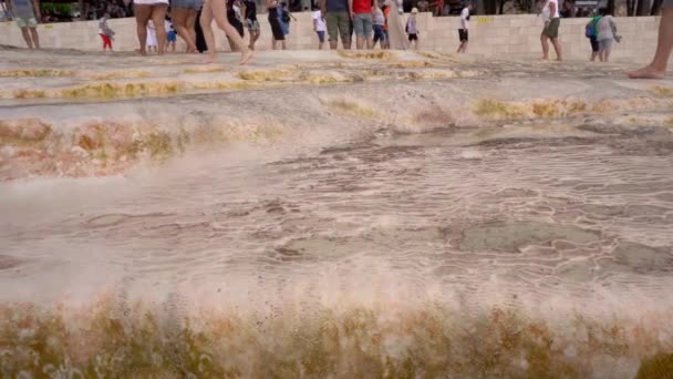 Legs of tourists seem walking barefoot on a naturally formed surface of pamukkale rich with calcium, Carbonate travertines the natural pools. Turkey - Filmagem, Vídeo