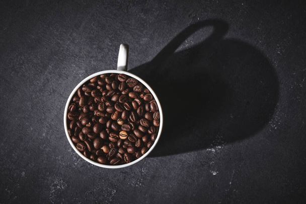 White cup of freshly brewed roasted coffee beans on gray background - Foto, immagini
