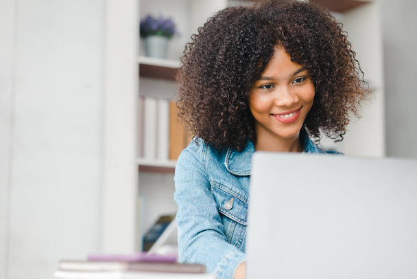 Американская женщина-подросток, сидящая в белом офисе с ноутбуком, она студент, обучающийся онлайн с ноутбуком дома, студент университета, обучающийся онлайн, онлайн-концепция веб-образования. - Фото, изображение