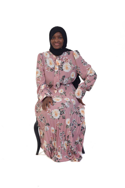 woman with burqa and flowered dress sitting in front and arm akimbo on white background - Foto, Imagen