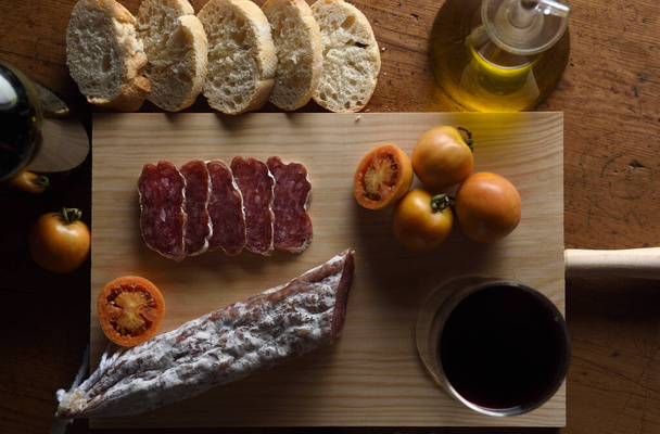 close up of a spanish food,tomato,wine,bread, sausage and olive oil on a wooden table - Foto, Bild