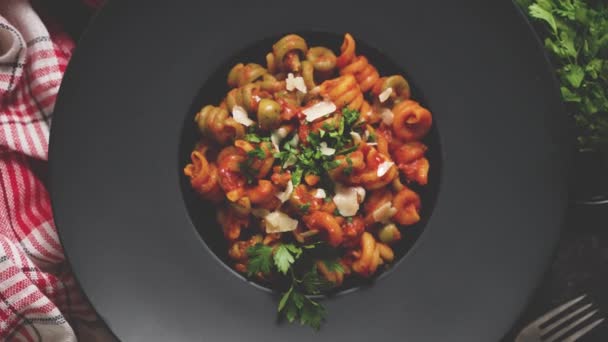 Вкусная аппетитная классическая итальянская паста с томатным соусом, сыром пармезан и базиликом на тарелке на темном столе. Вид сверху плоский лежал - Кадры, видео