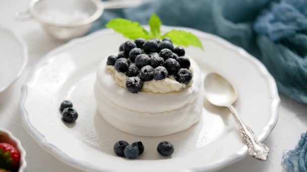 Delicious mini Pavlova meringue nest with blueberry and mint leaves served on white plate - Video, Çekim