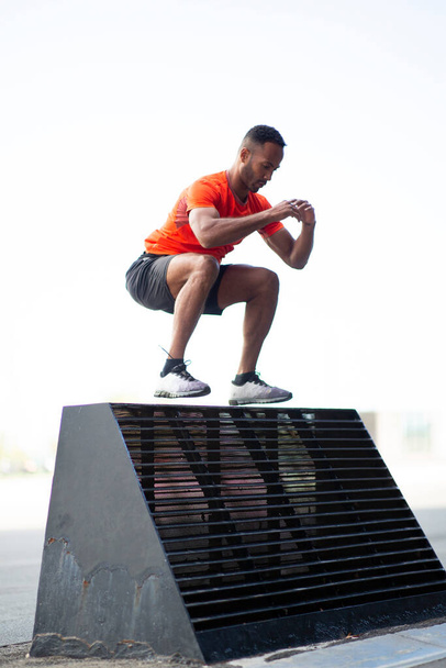 Adaptez l'athlète masculin effectuant un exercice de saut en hauteur à l'extérieur en ville pendant l'entraînement de cross fit - Photo, image