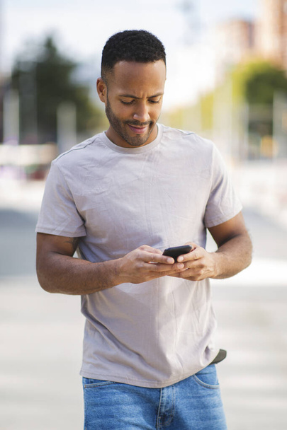 African american man text messaging using smartphone outdoors in city - Фото, зображення