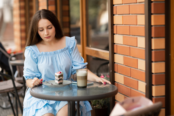 beautiful woman eating dessert in outdoor cafe, she has coffee break. people, street cafe concept - Photo, image