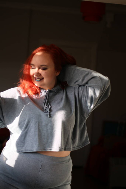 Plus size female with red hair wearing a grey lounge suit - Photo, Image