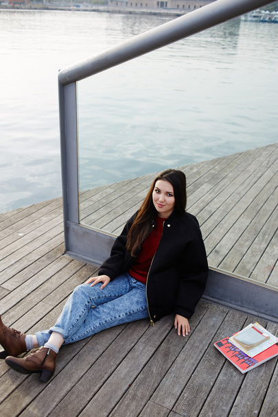 Charming tourist girl sitting on wooden pier enjoying beautiful view of Barcelona port - Foto, Imagem