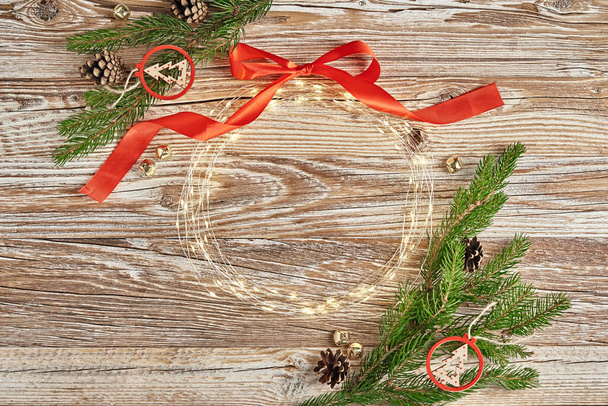 Новорічна композиція з гілками ялинки та гірляндою для освітлення на дерев'яному тлі. Різдвяна рамка, плоска. Різдвяний вітальний банер з копіювальним простором
 - Фото, зображення