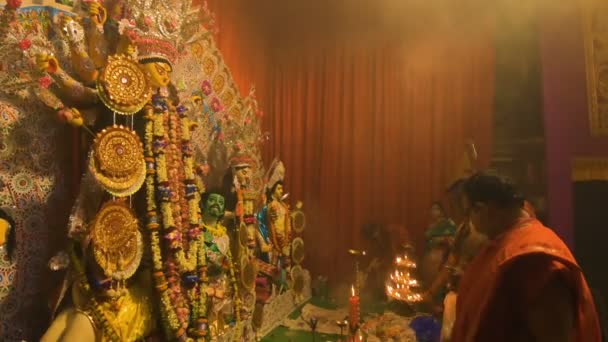 Howrah, India- October 15th, 2021 : Hindu purohits worshipping Goddess Durga with holy lamps and chamor on Sandhi Puja, the sacred juncture of Ashtami, eighth day and Nabami, nineth day, as ritual. - Imágenes, Vídeo