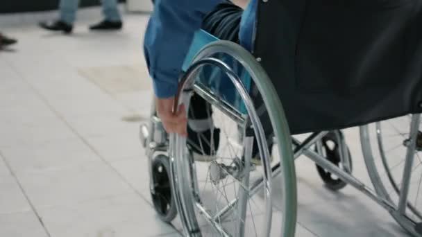 Paciente de edad avanzada con discapacidad crónica que utiliza silla de ruedas en la sala de espera en el área de recepción del hospital para reunirse con el médico para una cita. Hombre con problemas de salud haciendo visita de chequeo. De cerca.. - Metraje, vídeo
