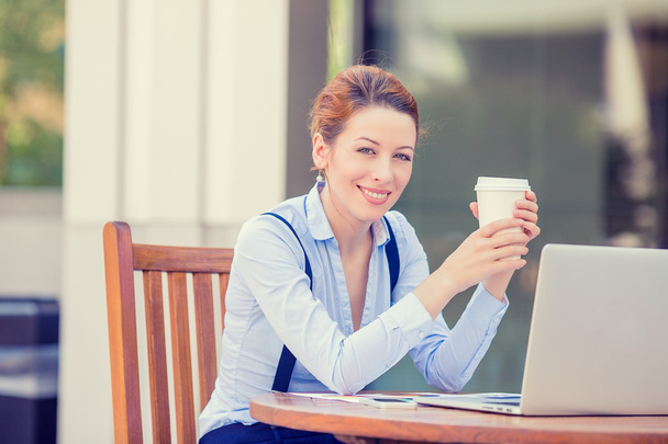 woman drinking coffee working on computer laptop outside corporate office - 写真・画像