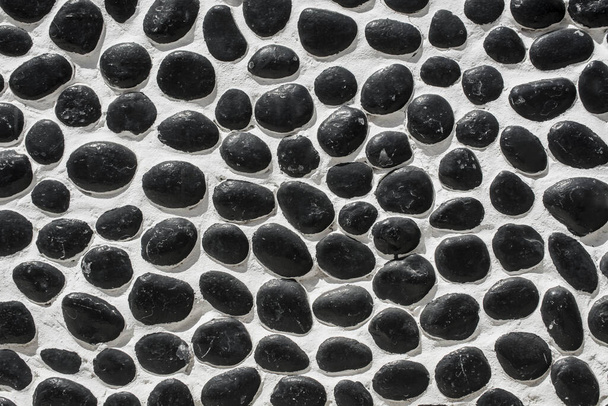 Wall closeup hand construction river round black stones closeup  - Fotografie, Obrázek