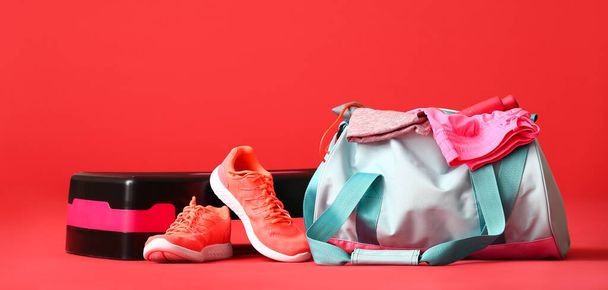 Αθλητική τσάντα, παπούτσια και stepper σε κόκκινο φόντο με χώρο για κείμενο - Φωτογραφία, εικόνα